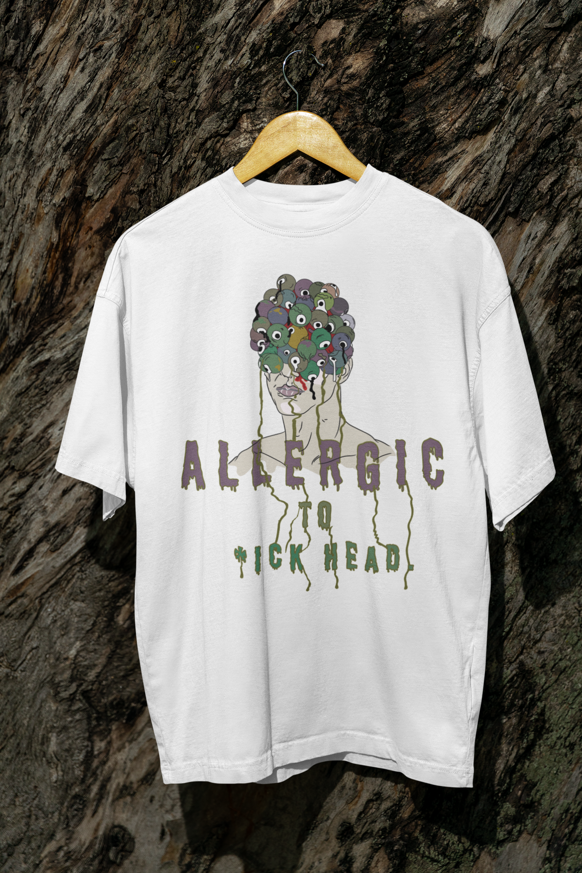 White oversized T-shirt reading "Allergic to Dickhead," styled outdoors; inclusive, gender-neutral streetwear top.