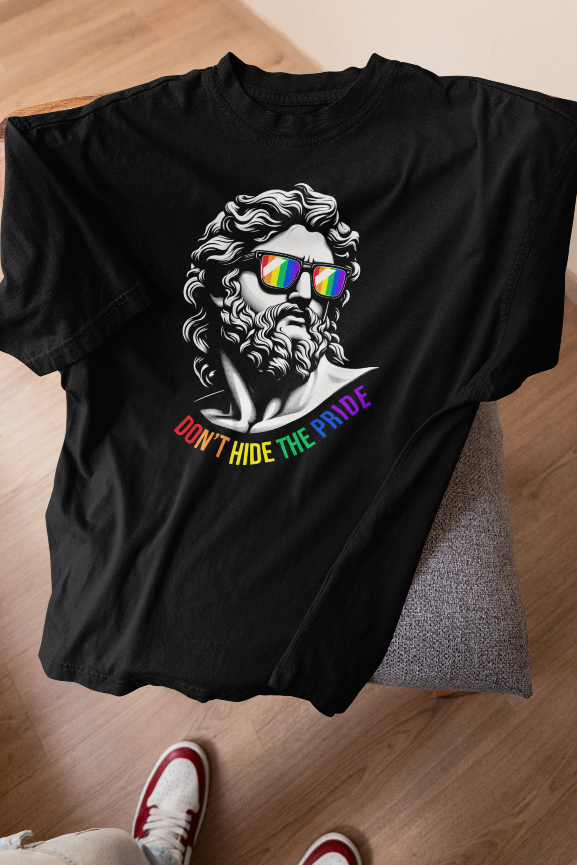 “Two gender-fluid models wearing ANTI’s black ‘Don’t Hide the Pride’ graphic T-shirts, featuring a statue-inspired face with rainbow sunglasses and Pride text, confidently posing in urban streetwear style.”

