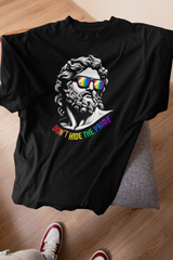 “Two gender-fluid models wearing ANTI’s black ‘Don’t Hide the Pride’ graphic T-shirts, featuring a statue-inspired face with rainbow sunglasses and Pride text, confidently posing in urban streetwear style.”


