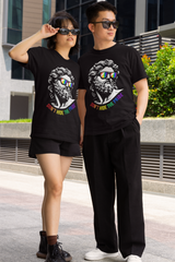 Two gender-fluid models confidently wearing ANTI's black unisex “Don’t Hide the Pride” streetwear tees featuring a Greek statue with rainbow sunglasses and bold LGBTQ+ slogan, posing outdoors in an urban setting.

