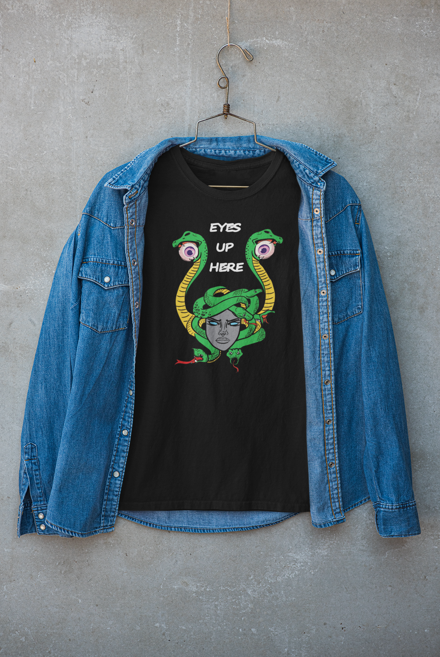 Unisex black graphic tee with “Eyes Up Here” slogan, layered under a casual jacket. Styled for bold, gender-fluid street fashion that defies expectations and amplifies identity.