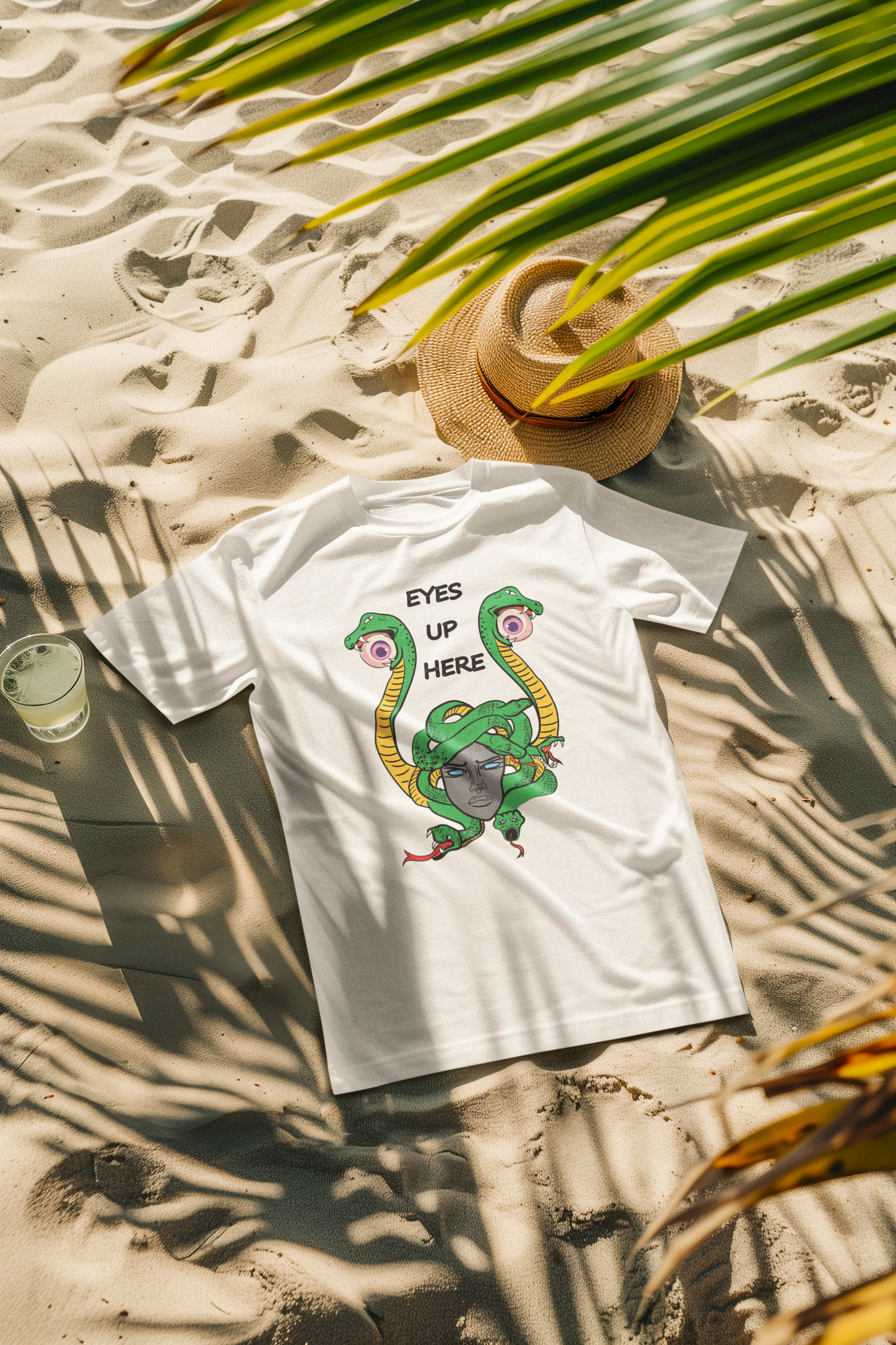 Unisex white T-shirt with “Eyes Up Here” printed text, modeled at the beach. A statement fashion piece celebrating Women, expression, freedom, and visibility in sun-soaked style.