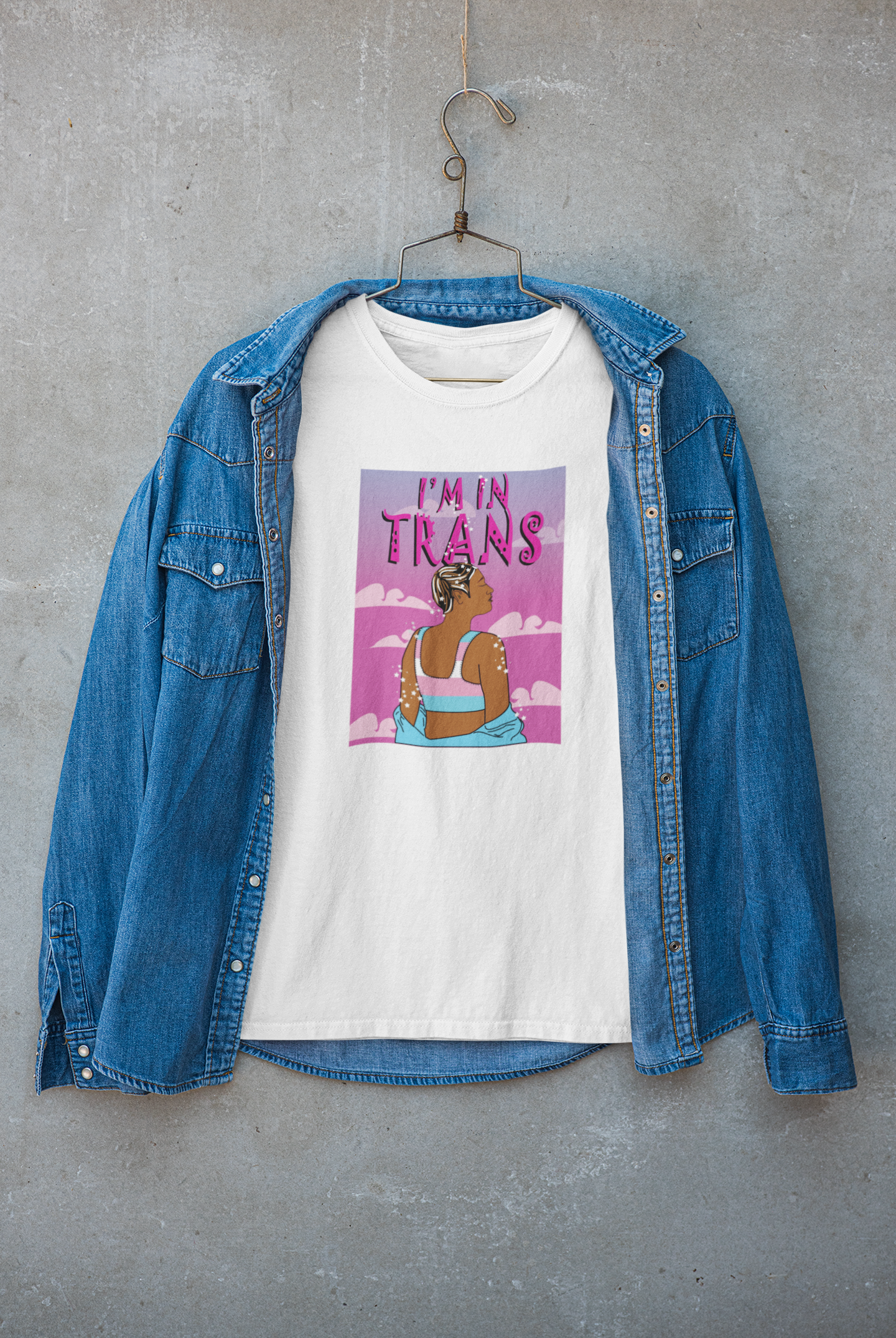 Crisp white "I’M IN TRANS" tee layered under a neutral-toned jacket, modeled with confidence by a gender-nonconforming individual; trans-affirming fashion by ANTI.