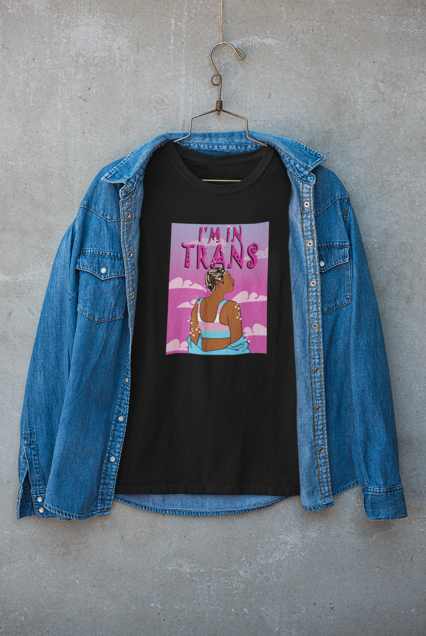 Edgy layered streetwear look featuring black "I’M IN TRANS" t-shirt under a dark jacket, styled by a queer model; bold, inclusive trans pride outfit by ANTI.

