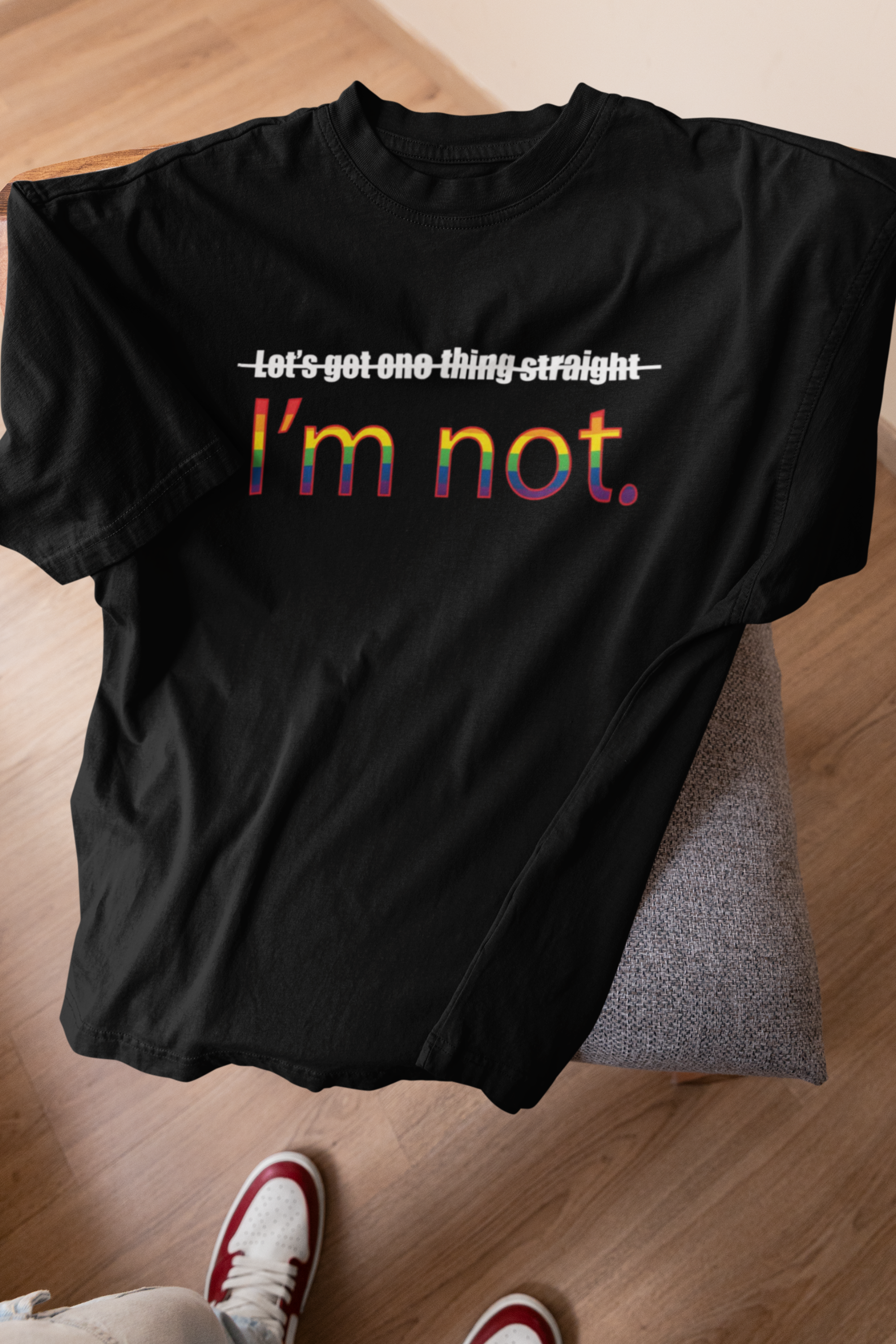 "Black oversized ANTI tee with ‘I’m NOT’ queer slogan draped on stool – gender-fluid pride fashion for all identities."