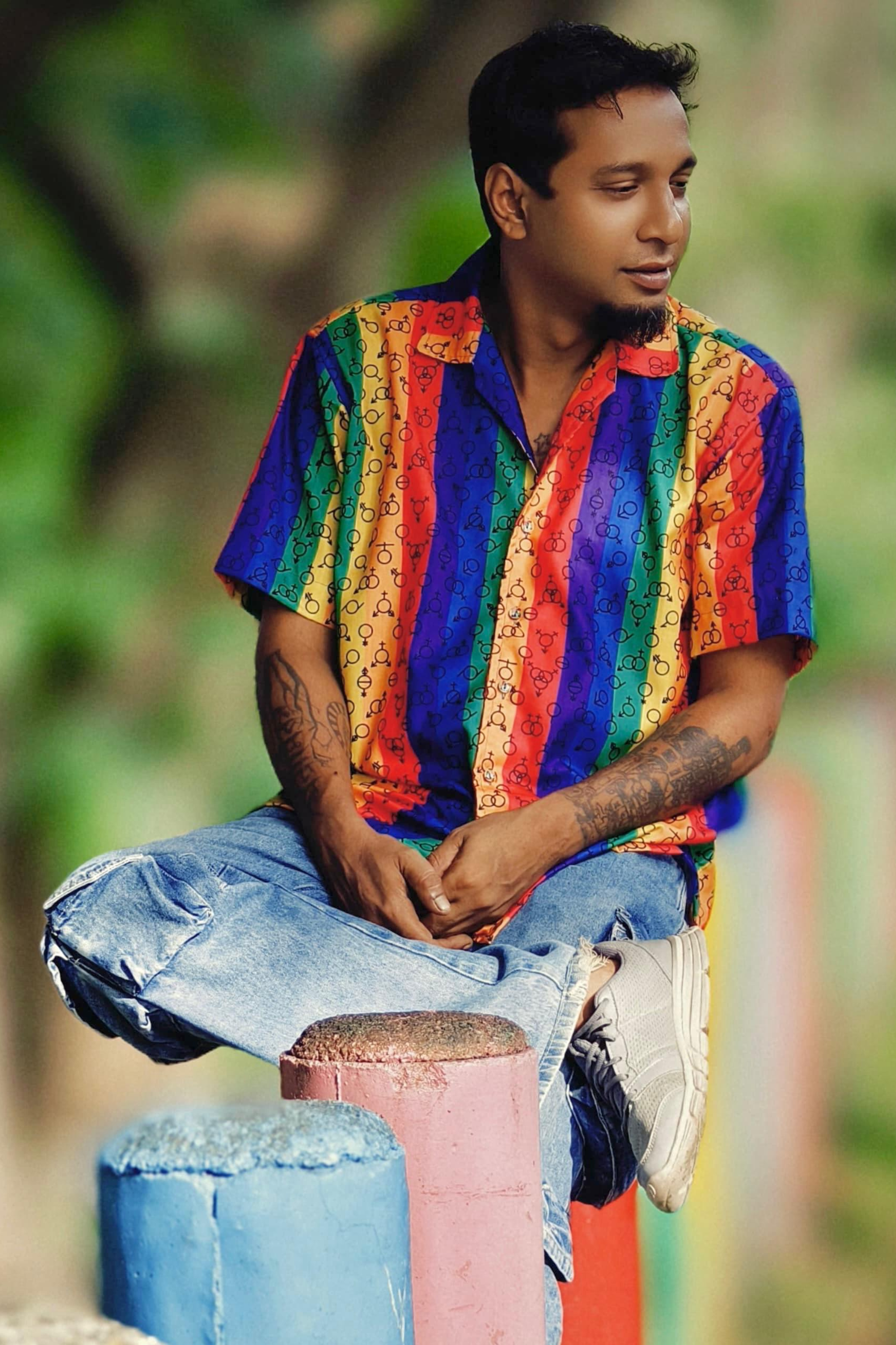 Bright, collared shirt with glowing neon rainbow stripes and repeated gender symbols in black, representing inclusivity and gender fluidity. Designed by ANTI to empower LGBTQ+ expression through fashion.