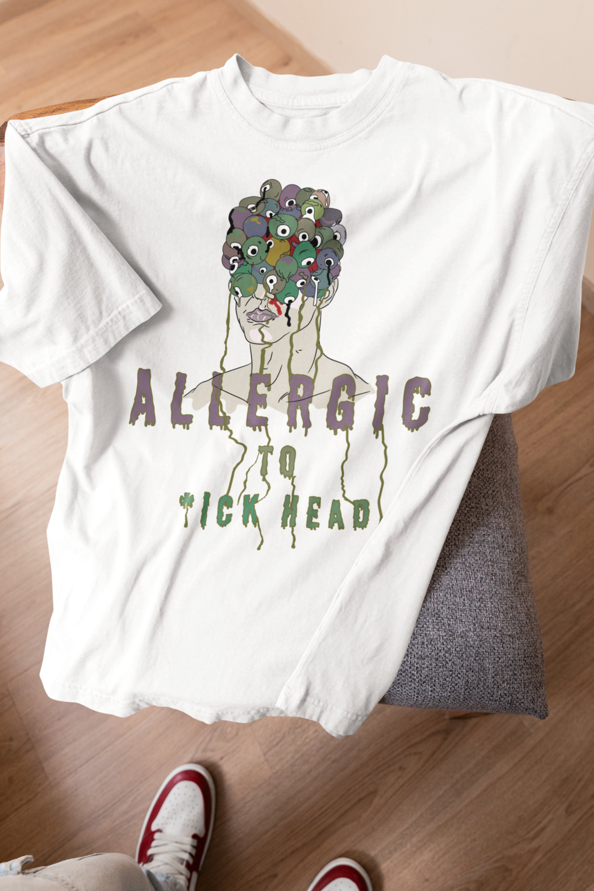 White oversized T-shirt with rebellious print, styled on stool; inclusive, gender-fluid streetwear design.