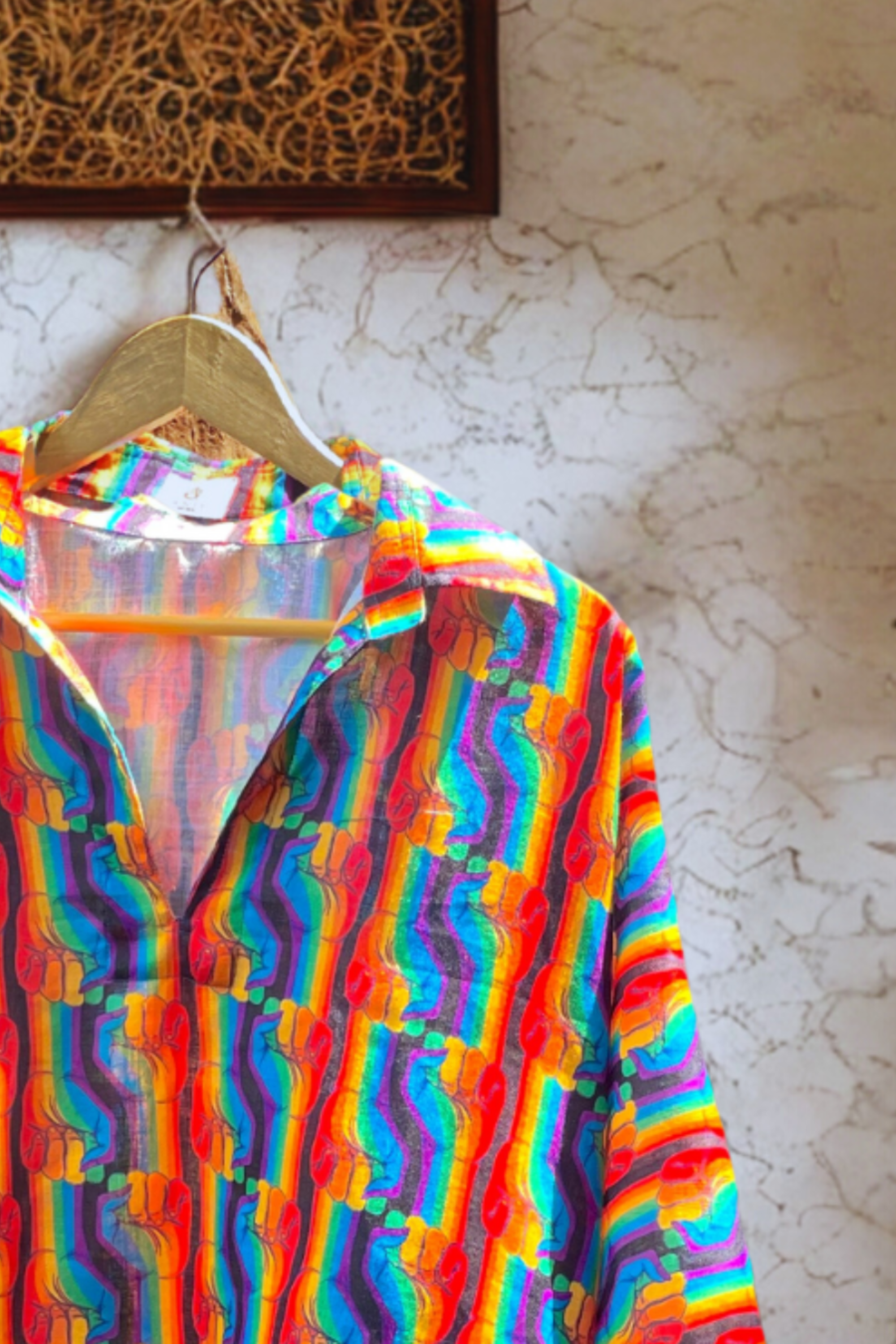 Close-up of ANTI Spectrum Shout shirt collar showing lustrous silk-blend fabric and multicolor fist pattern, capturing premium craftsmanship and gender-fluid styling.
