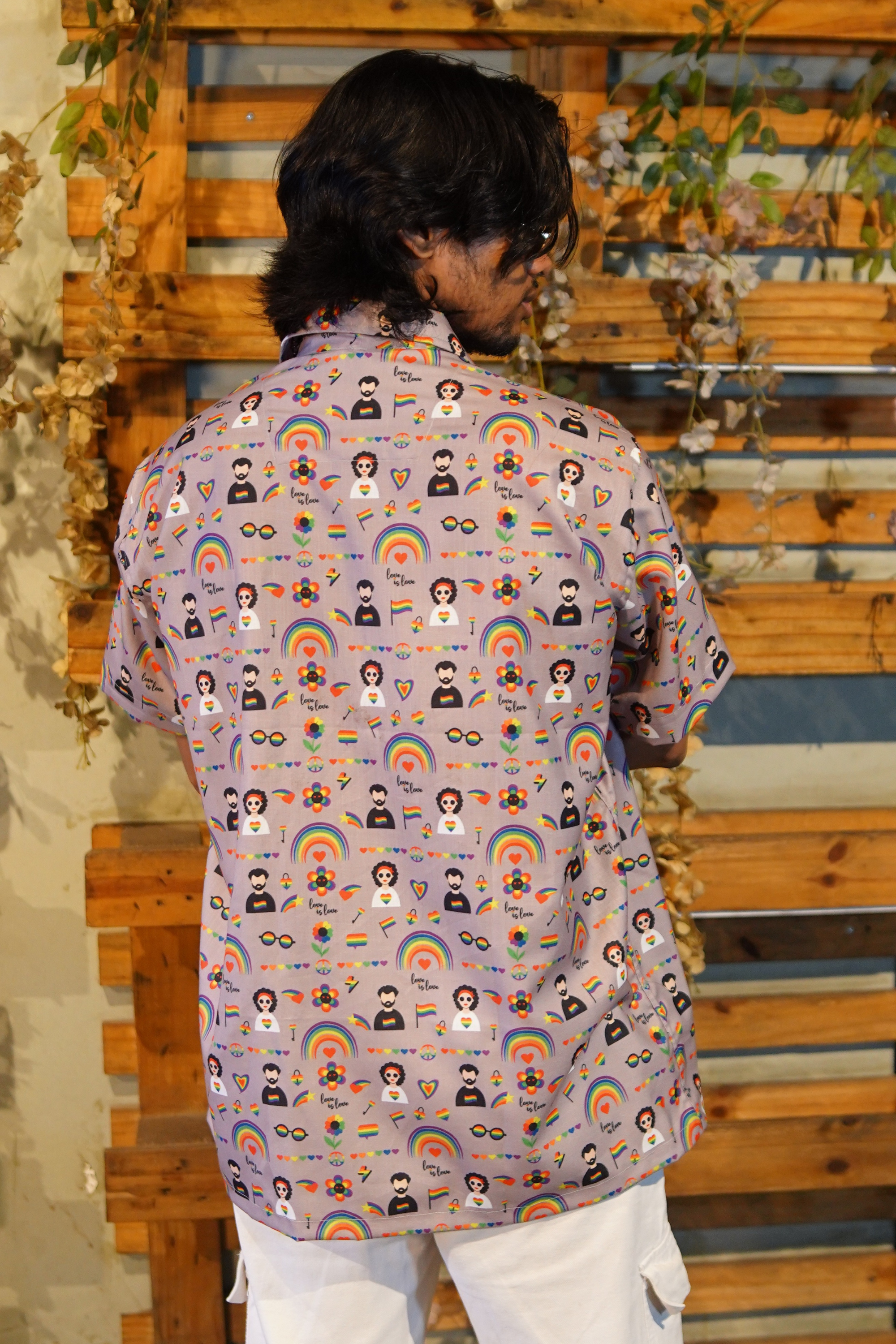 Person wearing a patterned shirt with various designs against a wooden background