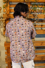 Person wearing a patterned shirt with various designs against a wooden background