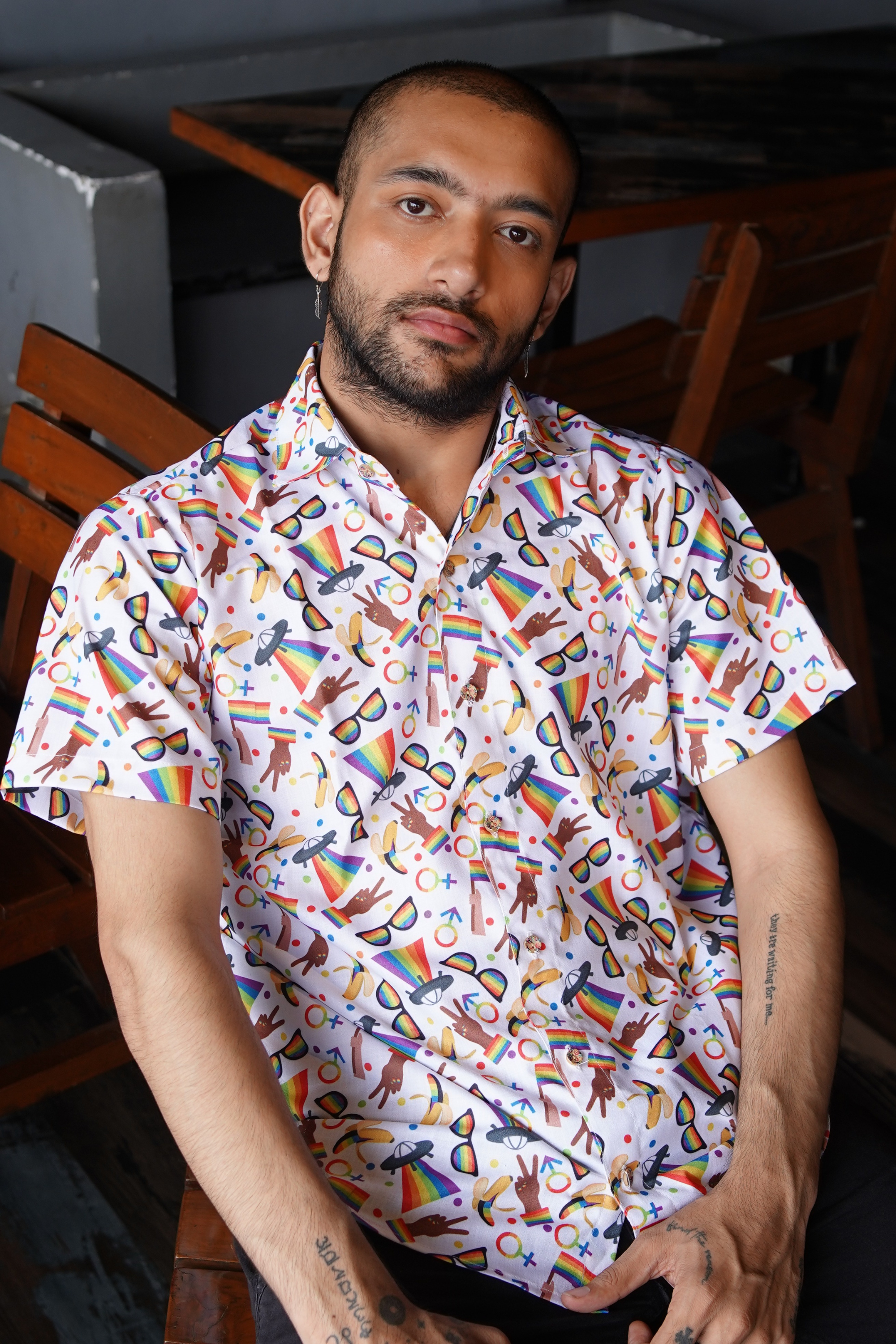 Man wearing a colorful patterned shirt sitting indoors.