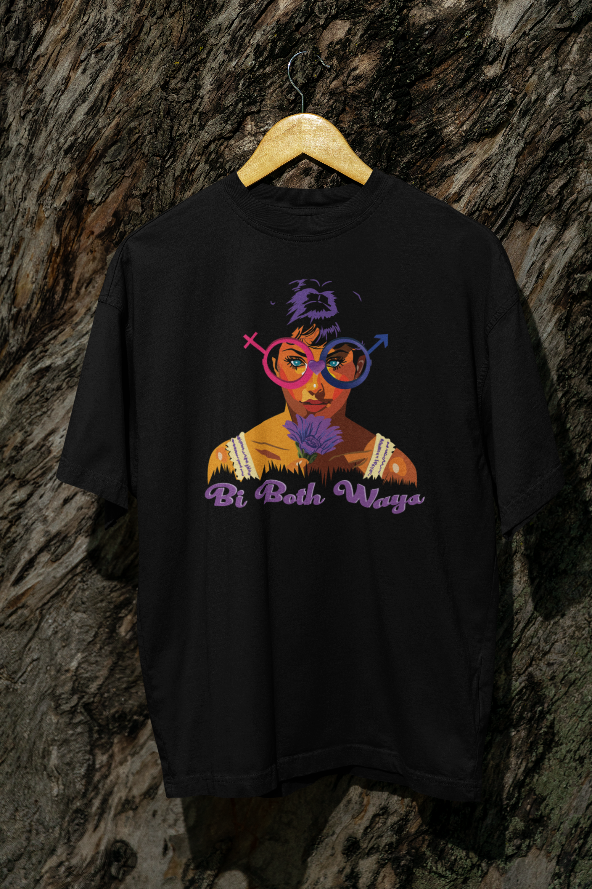 Black Bi Both Ways oversized t-shirt hanging from a tree outdoors, featuring bi pride artwork in a bold, nature-inspired setting.