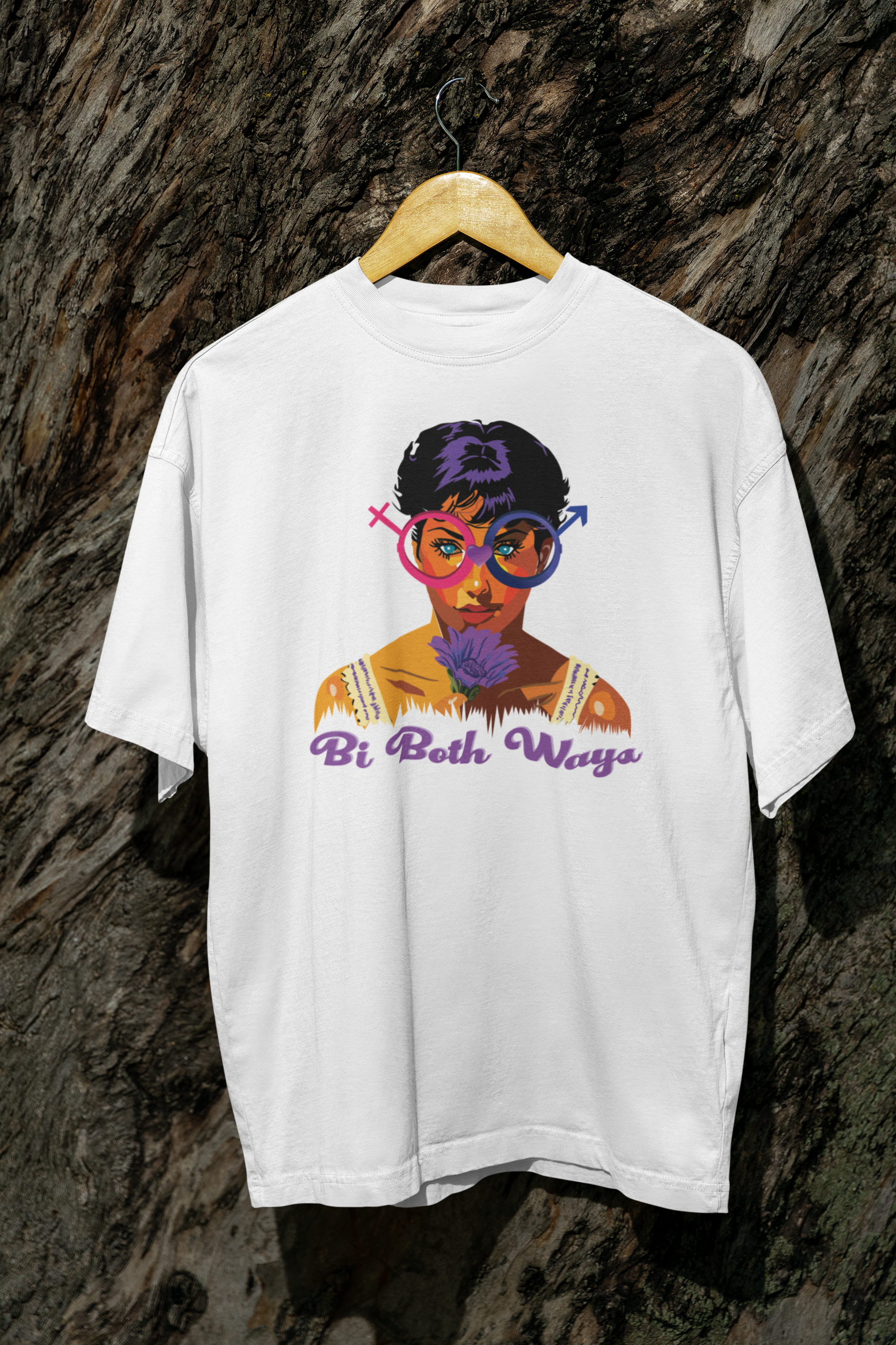 White Bi Both Ways oversized t-shirt hanging on a tree branch, with bi pride graphic visible against natural outdoor background.