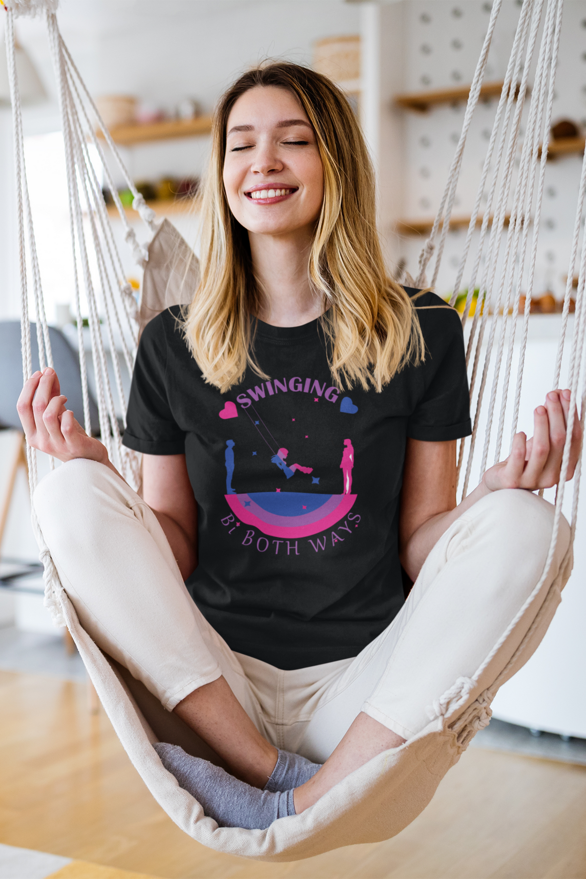 Close-up of black t-shirt showcasing bold white “SWINGING Bi BOTH WAYS” graphic; bisexuality-themed fashion supporting visibility and inclusivity for LGBTQIA+ individuals.