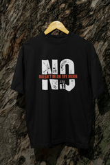 Black oversized t-shirt with bold consent slogan, unisex streetwear style, displayed outdoors on tree for edgy vibe