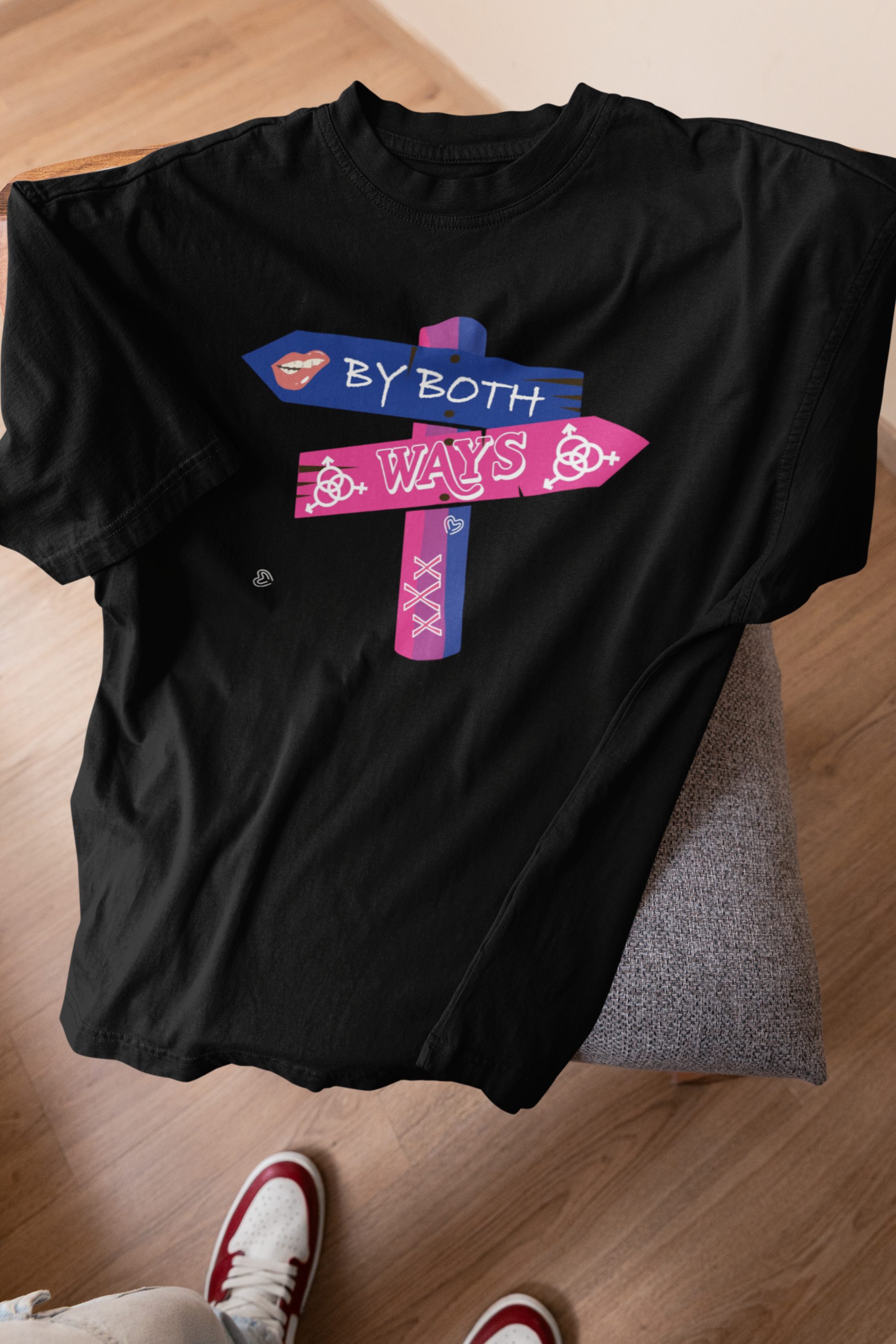 Black oversized gender-neutral T-shirt with “By Both Ways” slogan displayed on a stool against neutral backdrop

