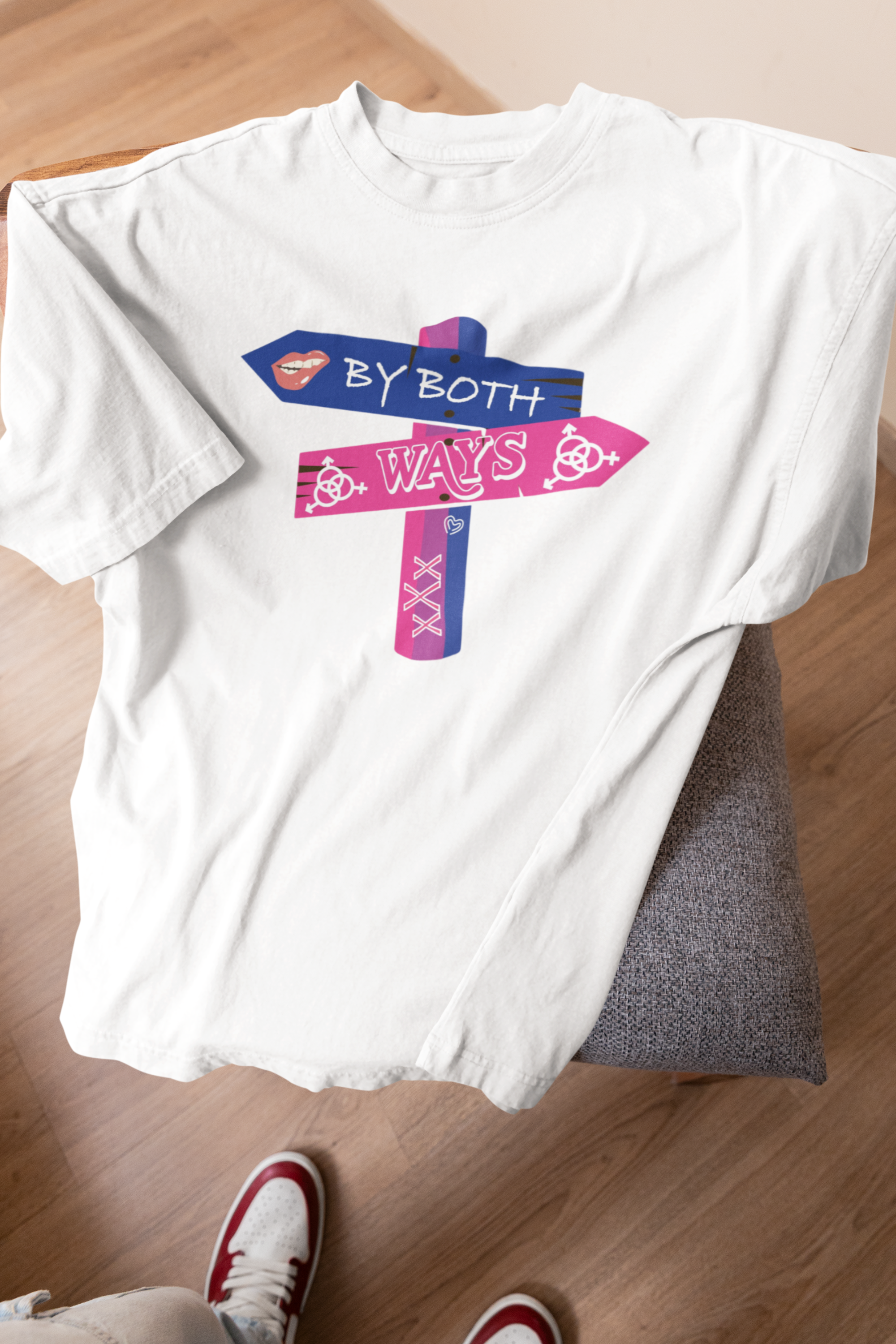 White oversized unisex T-shirt with “By Both Ways” slogan draped on a stool, designed for fluid expression