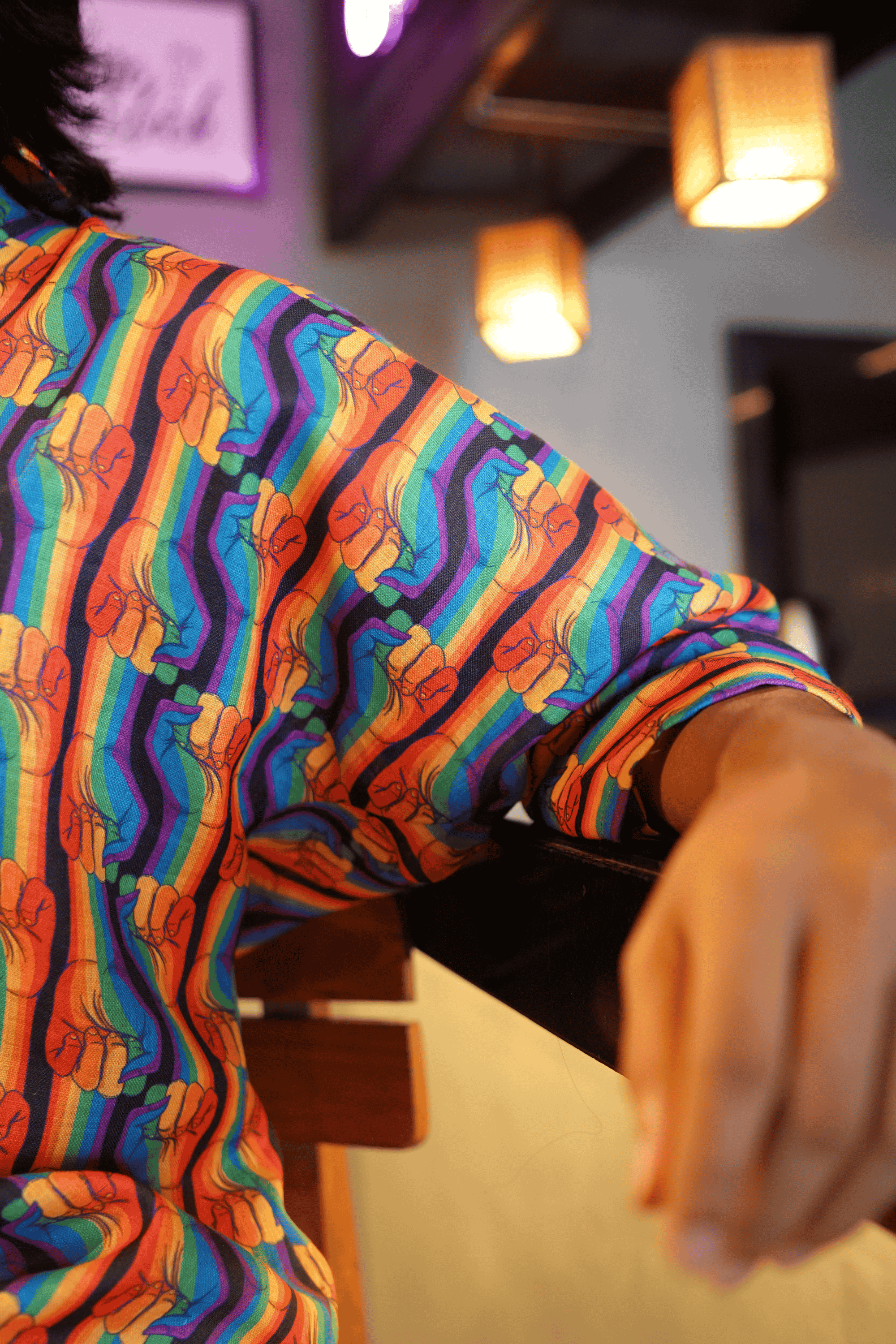 Close-up of soft cotton fabric featuring repeated rainbow-striped protest fists, symbolizing LGBTQIA+ pride, solidarity, and rebellion.
