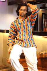 Detailed fabric view of rainbow-striped shirt with repeated clenched fist print symbolizing LGBTQ+ pride and protest.