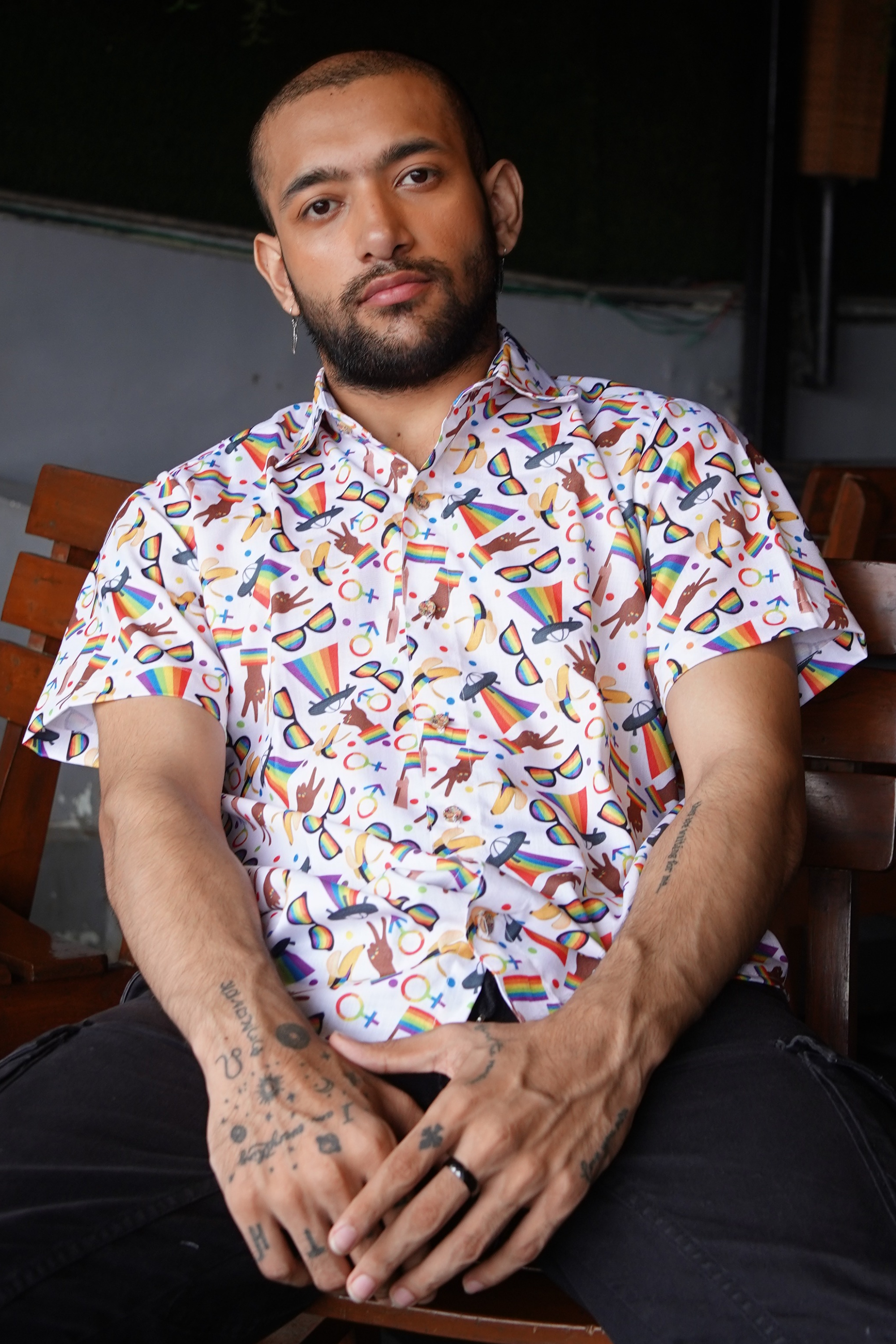 Man wearing a colorful patterned shirt sitting indoors.