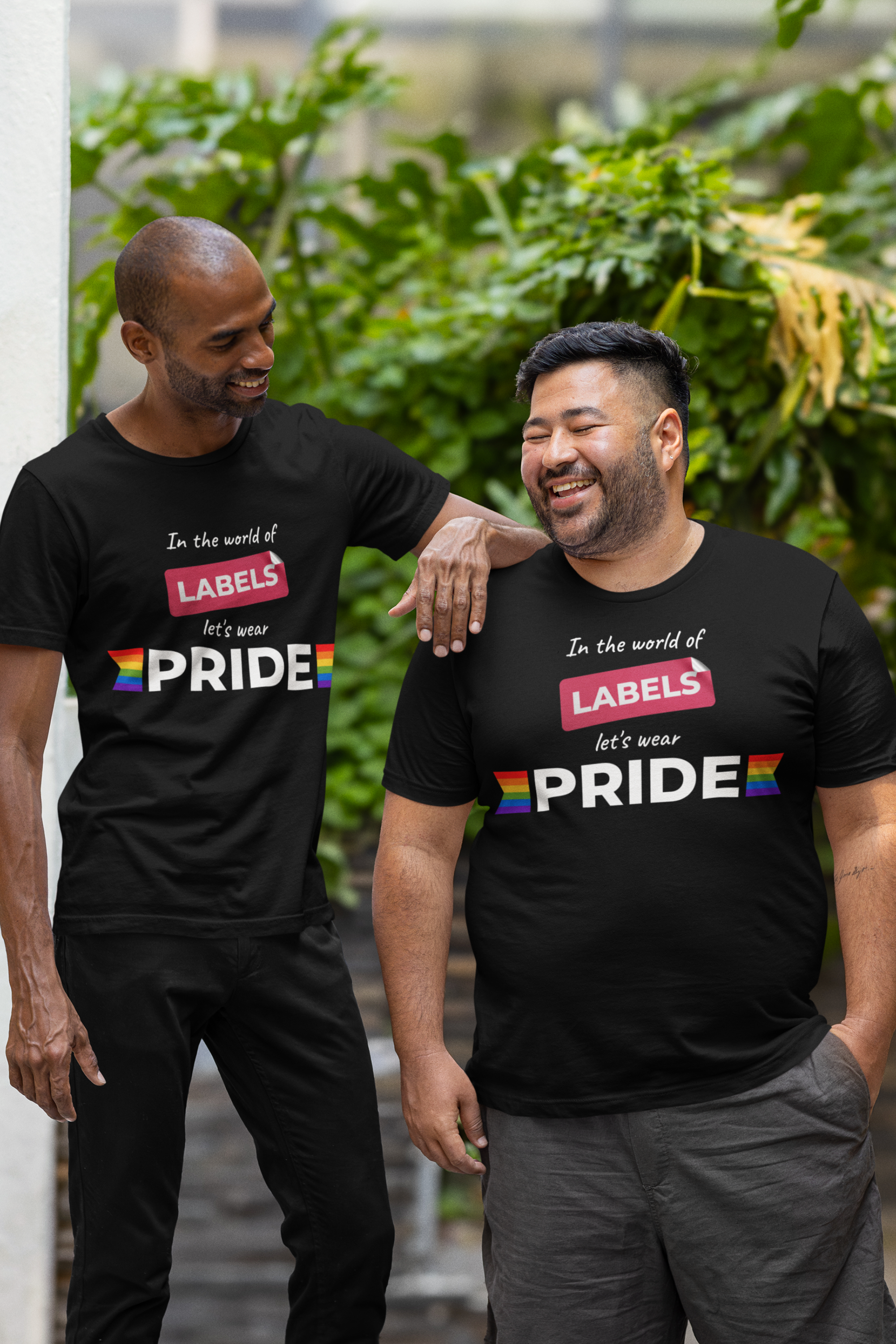 Two gender-diverse individuals wearing matching black ANTI t-shirts with the phrase “In the world of labels, let’s wear pride,” featuring rainbow flag accents. Perfect for LGBTQIA+ pride, inclusive identity expression, and bold, gender-fluid fashion.

