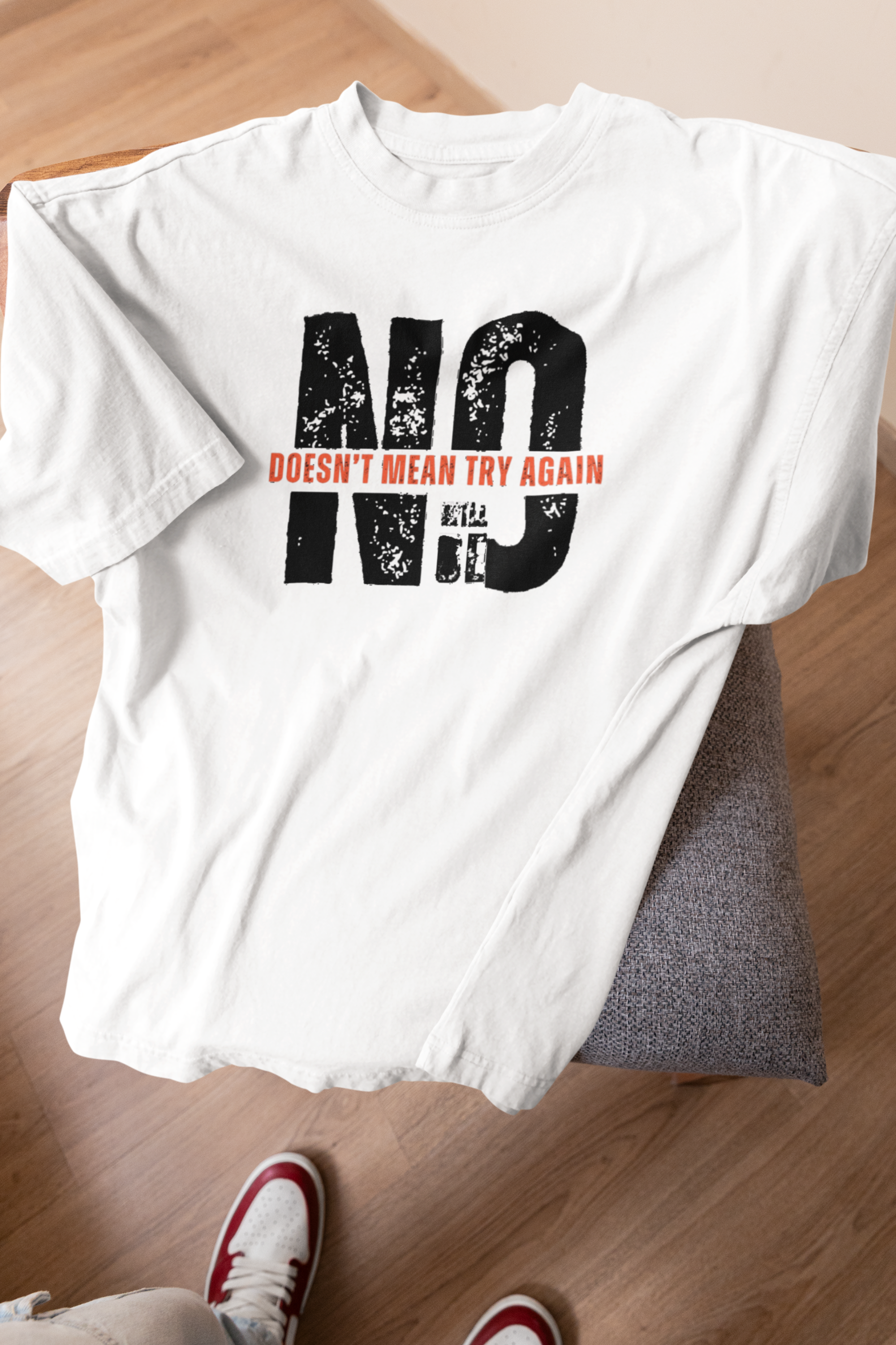 White gender-neutral t-shirt with consent messaging, laid on stool, oversized cotton, part of queer streetwear drop