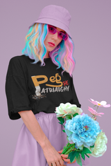 Flatlay image of a black oversized cotton t-shirt with bold white “Peg the Patriarchy” text. A powerful feminist statement piece by ANTI, designed to challenge gender norms and celebrate women's strength, autonomy, and rebellion through fearless fashion.