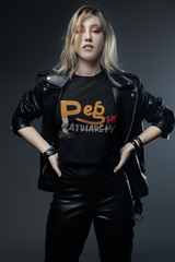 Confident model in black leather jacket and pants wearing ANTI’s PEG THE PATRIARCHY unisex t-shirt featuring a bold typographic design that disrupts power and gender norms with an unapologetically queer, punk-inspired aesthetic.

