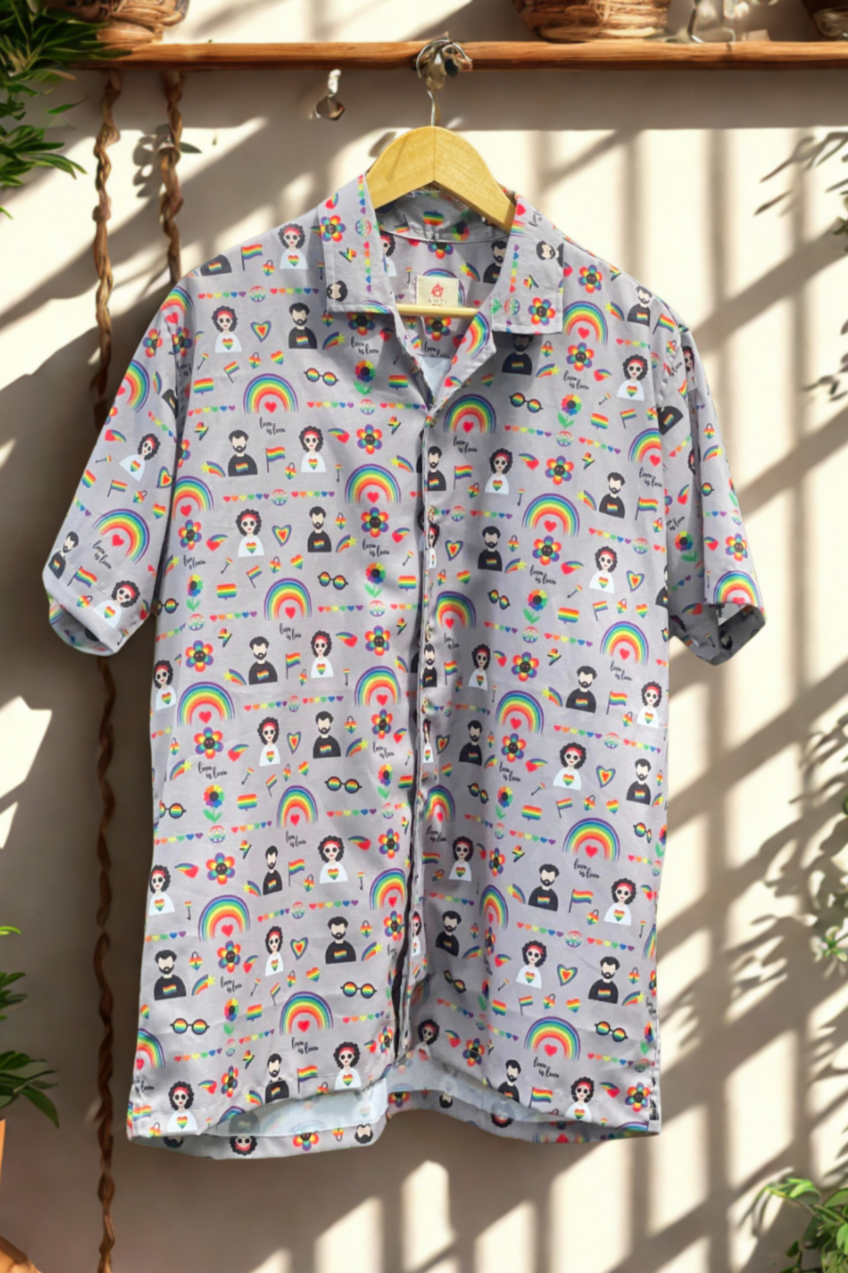 Unisex short-sleeve button-down shirt with vibrant LGBTQIA+ pride icons including rainbows, flags, queer figures, and ‘Love is Love’ slogans, designed by ANTI. Gender-fluid fashion for inclusive expression.