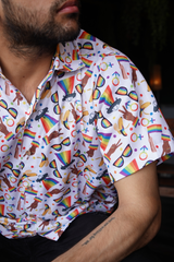 Person wearing a colorful patterned shirt with rainbow designs and symbols.