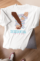 White “SEXSSENTIAL CRISIS” gender-fluid t-shirt laid flat on a soft chair, showcasing an empowering graphic of two diverse hands clasped and bound together with the trans flag, symbolizing queer solidarity and resistance.

