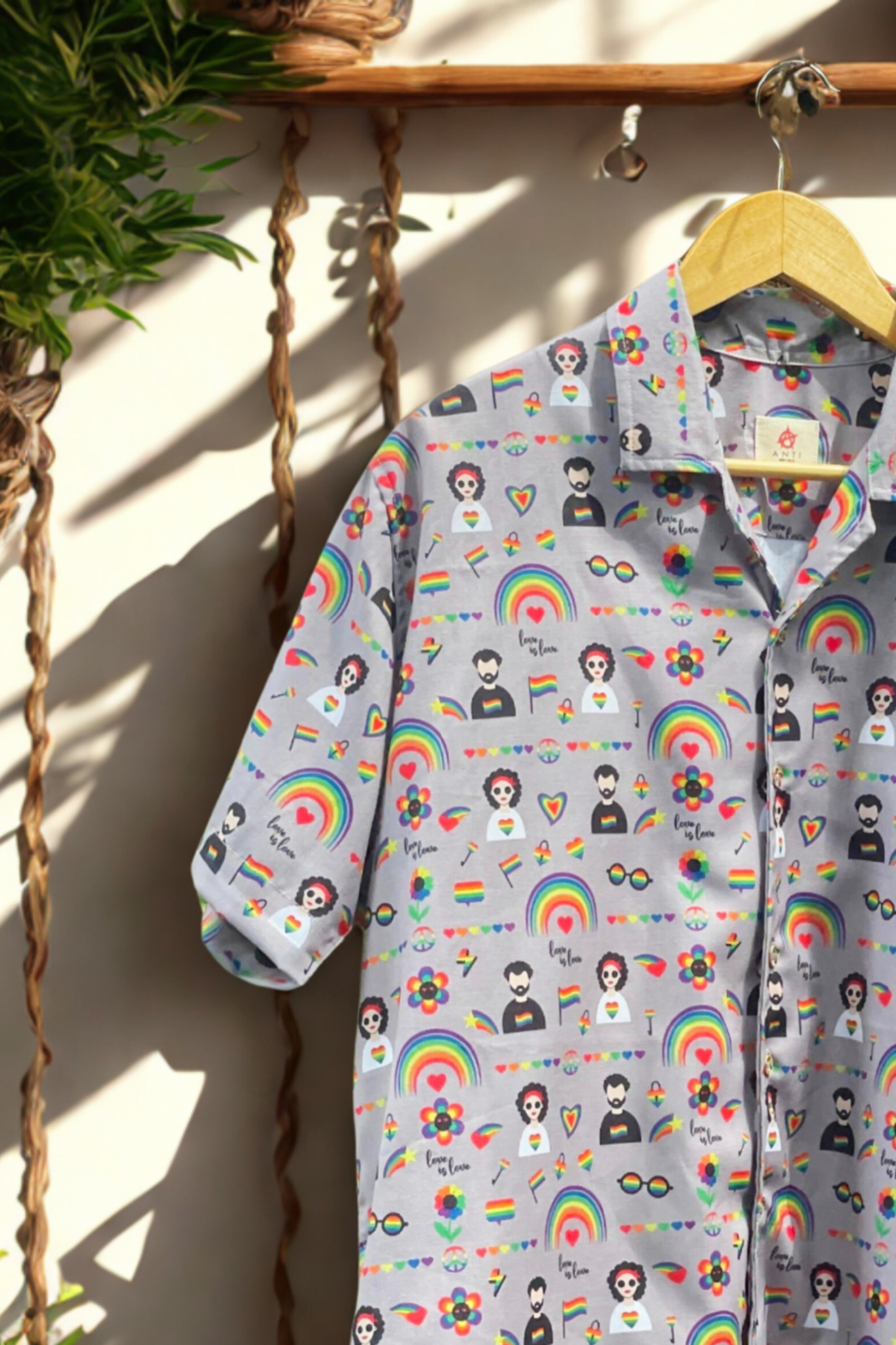 Side view of inclusive fashion pride shirt by ANTI featuring rainbow hearts, queer characters, and affirming prints, captured in warm sunlight for gender-fluid style inspiration.