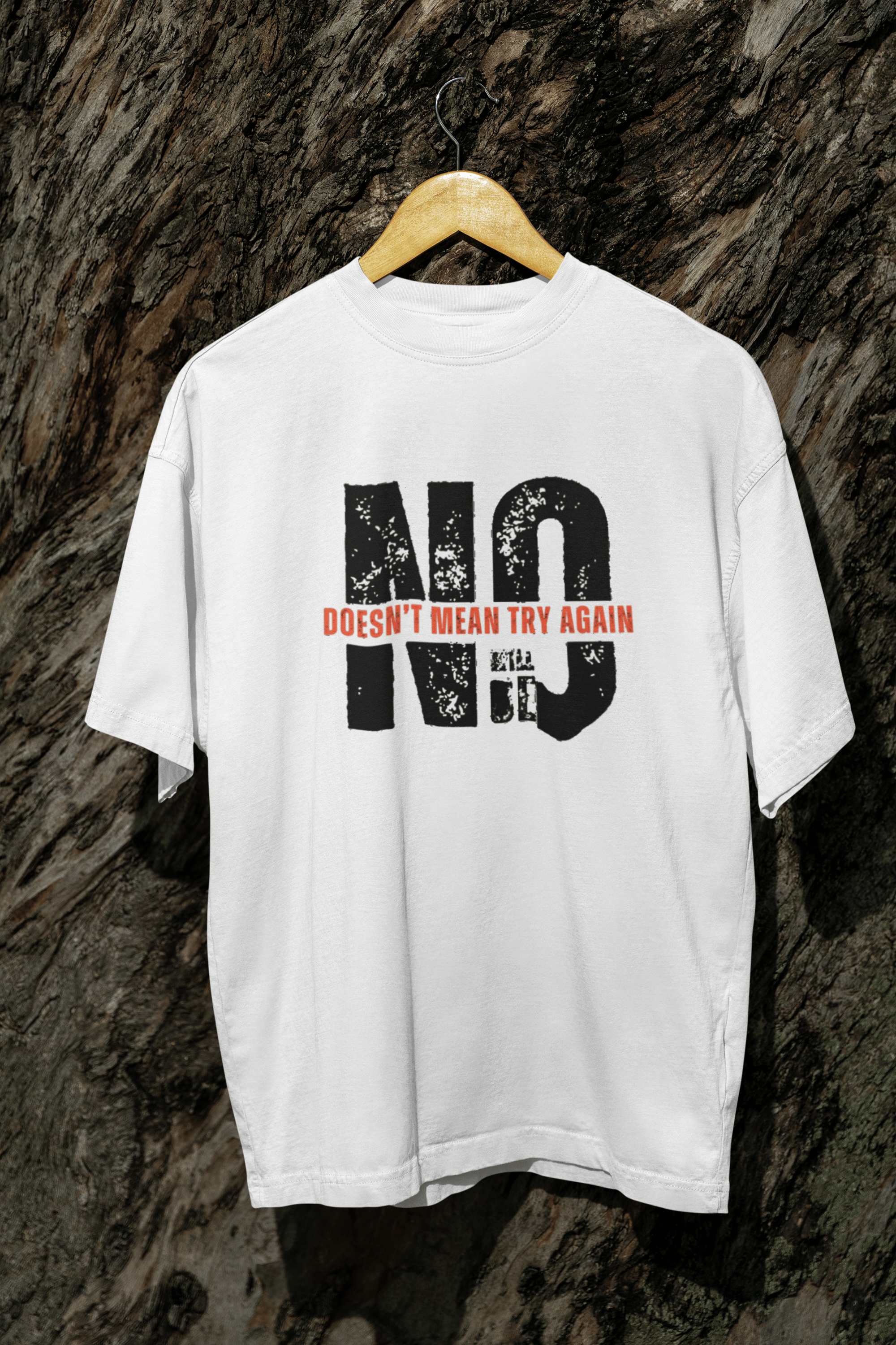 White oversized t-shirt with “No doesn’t mean try again” slogan, gender-fluid fit, hanging on tree, inclusive fashion