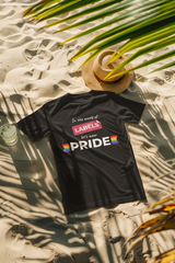 Black t-shirt featuring the phrase “In the world of LABELS, let's wear PRIDE” laid on sandy beach under tropical palm shadows, celebrating inclusive fashion and self-expression by ANTI.